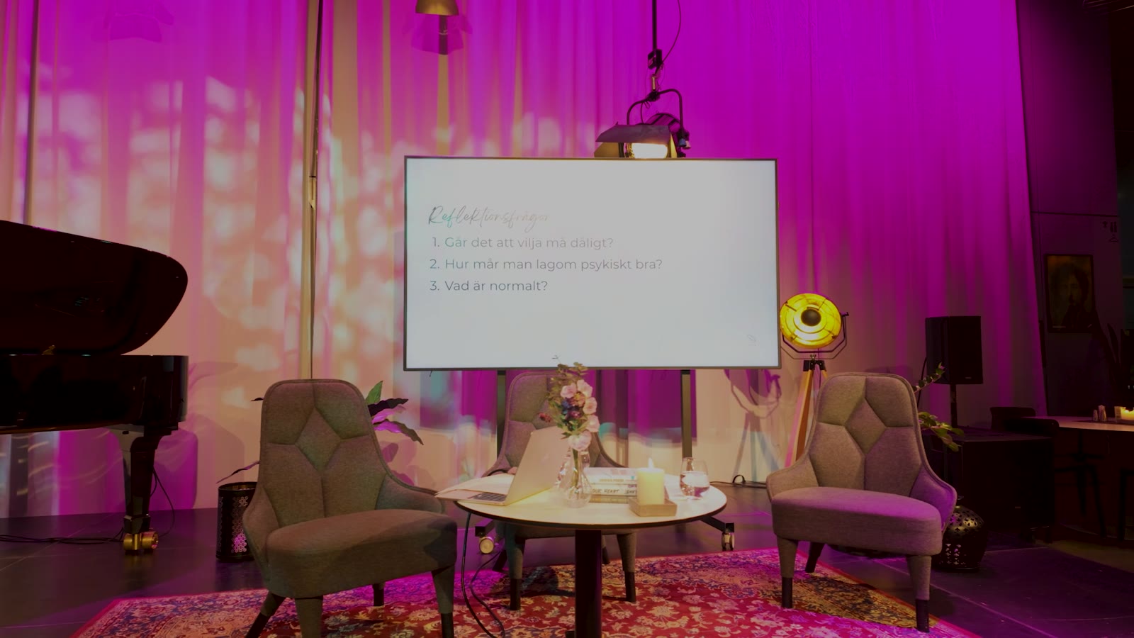 Scenen inför samtalet, med flygel och fåtöljer i rosa ljus