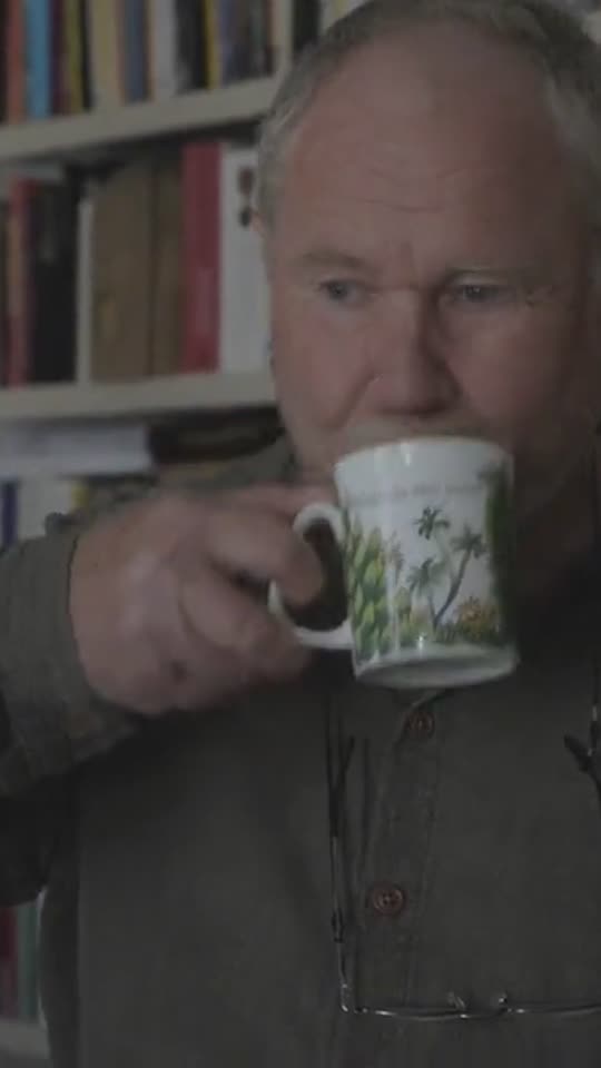 Gäst som dricker kaffe framför bokhyllan