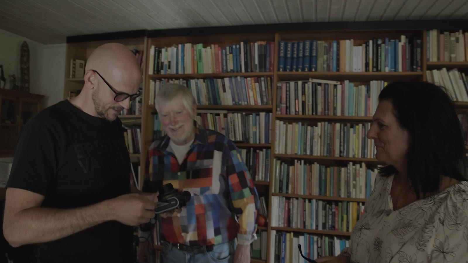 Programledarna hälsar på hos en gäst bland bokhyllorna
